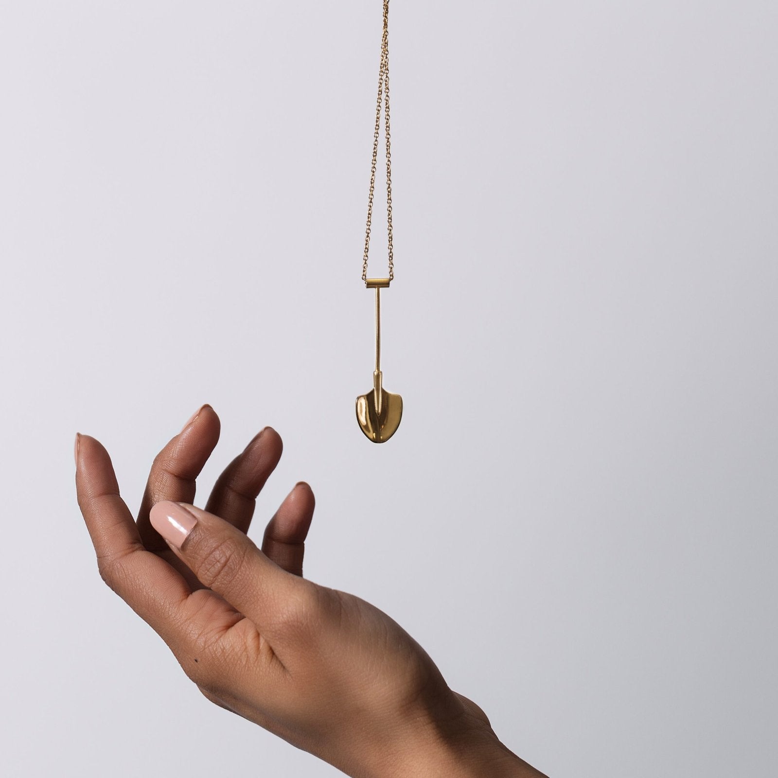 gold shovel pendant dangling from hand – Spade In Chelsea ravegear