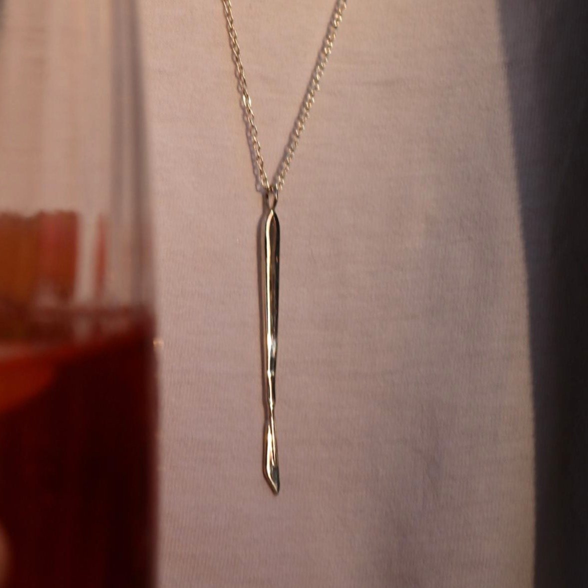 lifestyle shot of Scalpelle Silver – surgeon gift necklace with drink